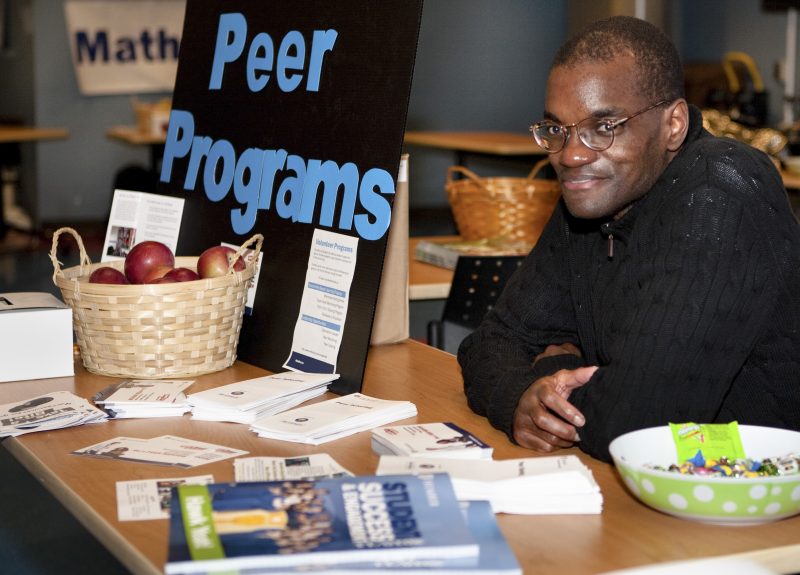 Man sitting behind table, with flyers