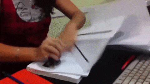 A woman rapidly staples a stack of paperwork.