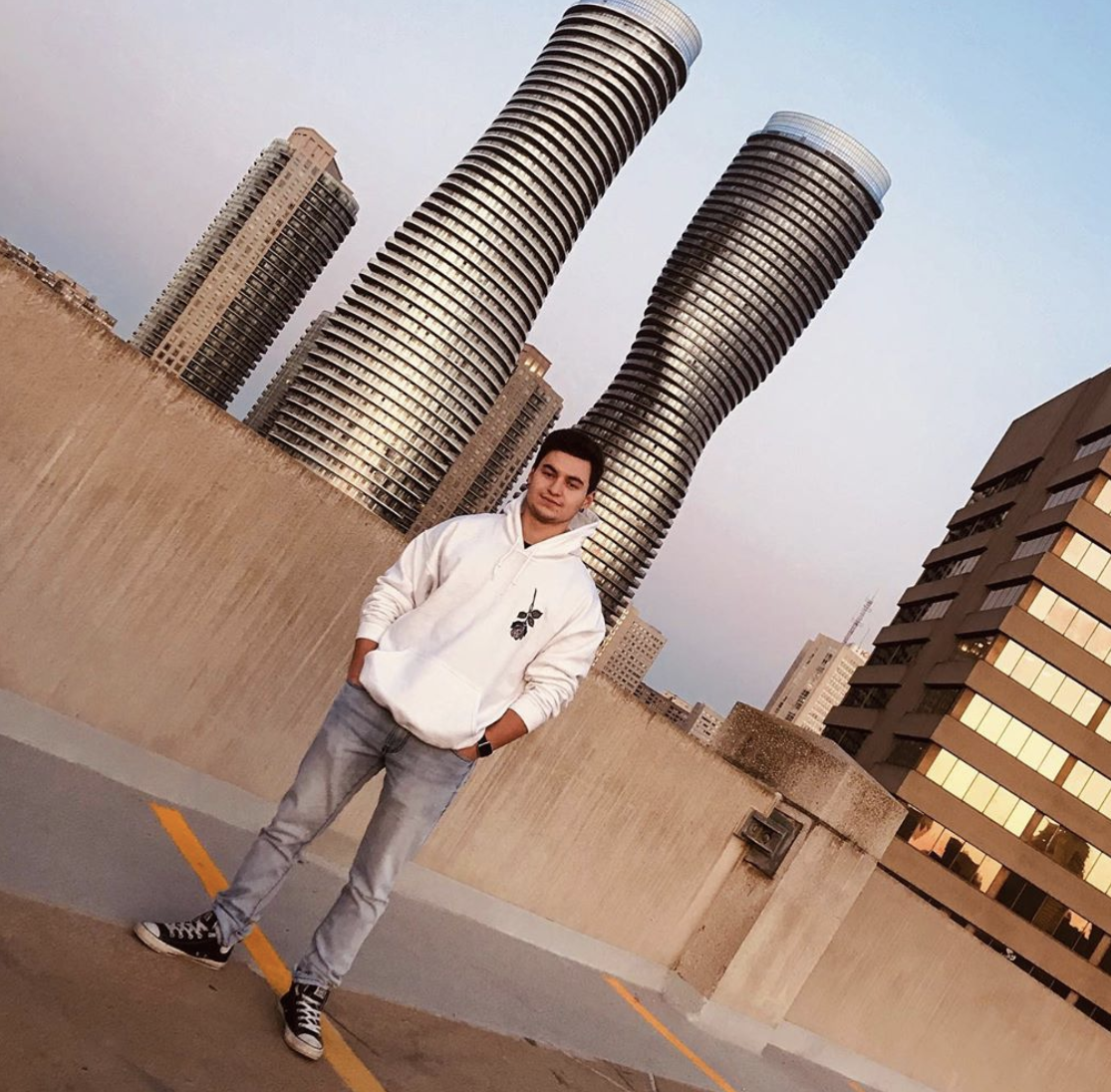Second year Humber College Business administration student Mitch Carreiro stands outside in a white hoodie and jeans.