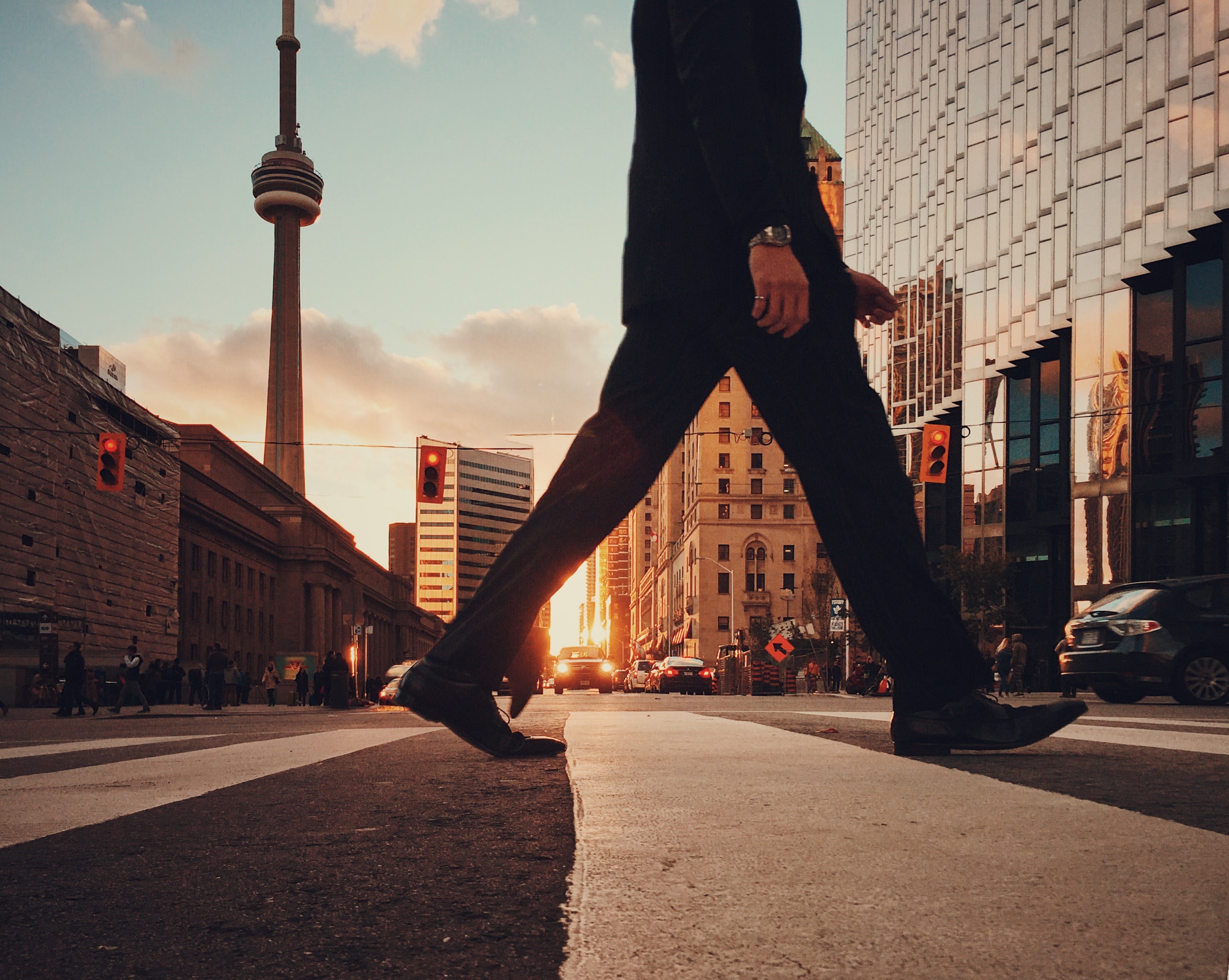 Sunset over Toronto street with a man in a suit walk across the street