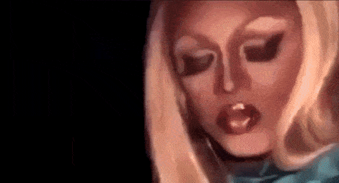 Drag queen Mayhem Miller wears a turquoise top and dramatic makeup and stares intensely into the camera.