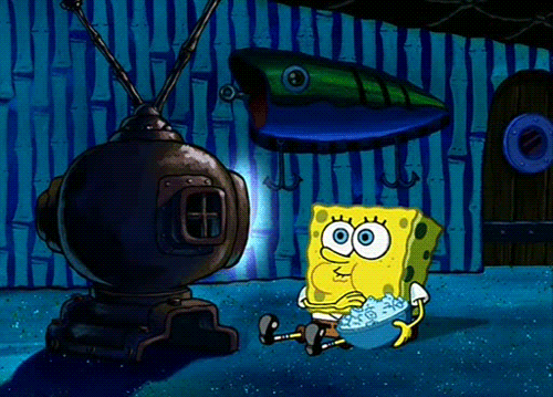 Spongebob Squarepants sits in front of the TV and happily eats popcorn.