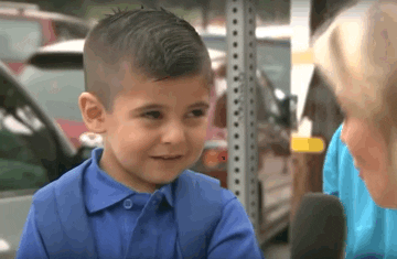 A young boy being interviewed by a news reporter smiles and then quickly begins to sob.