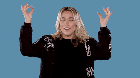 Greek pop singer Jessica "Josephine" Wendel wears a black sweater while holding her hands above her head and taking a deep breath.