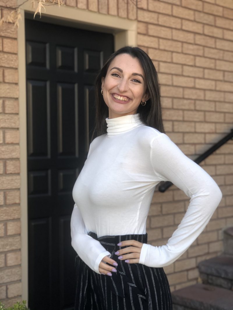 Photo of Jack.org intern, Hailey Appel, smiling in front of door and staircase.
