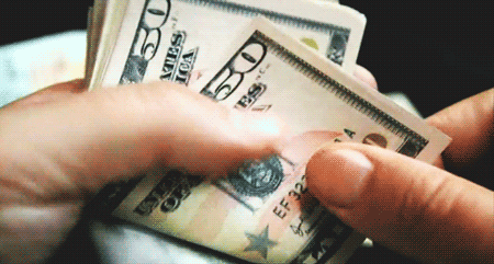 Close-up of a person's hands sifting through a stack of American $50 bills.