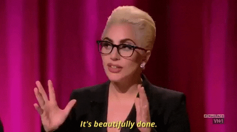 Pop star Lady Gaga wears a black blazer and matching black glasses with her blonde hair in a sleek updo. She says, "It's beautifully done."