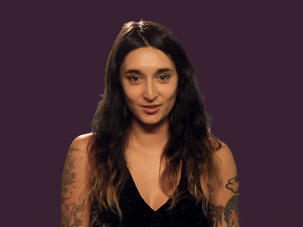 A woman points to her eyes and then points to the camera.