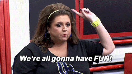 Abby Lee Miller from Lifetime's "Dance Moms" wears a black shirt and points her finger while shouting, "We're all gonna have fun."