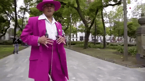 A man poses in a pink suit.