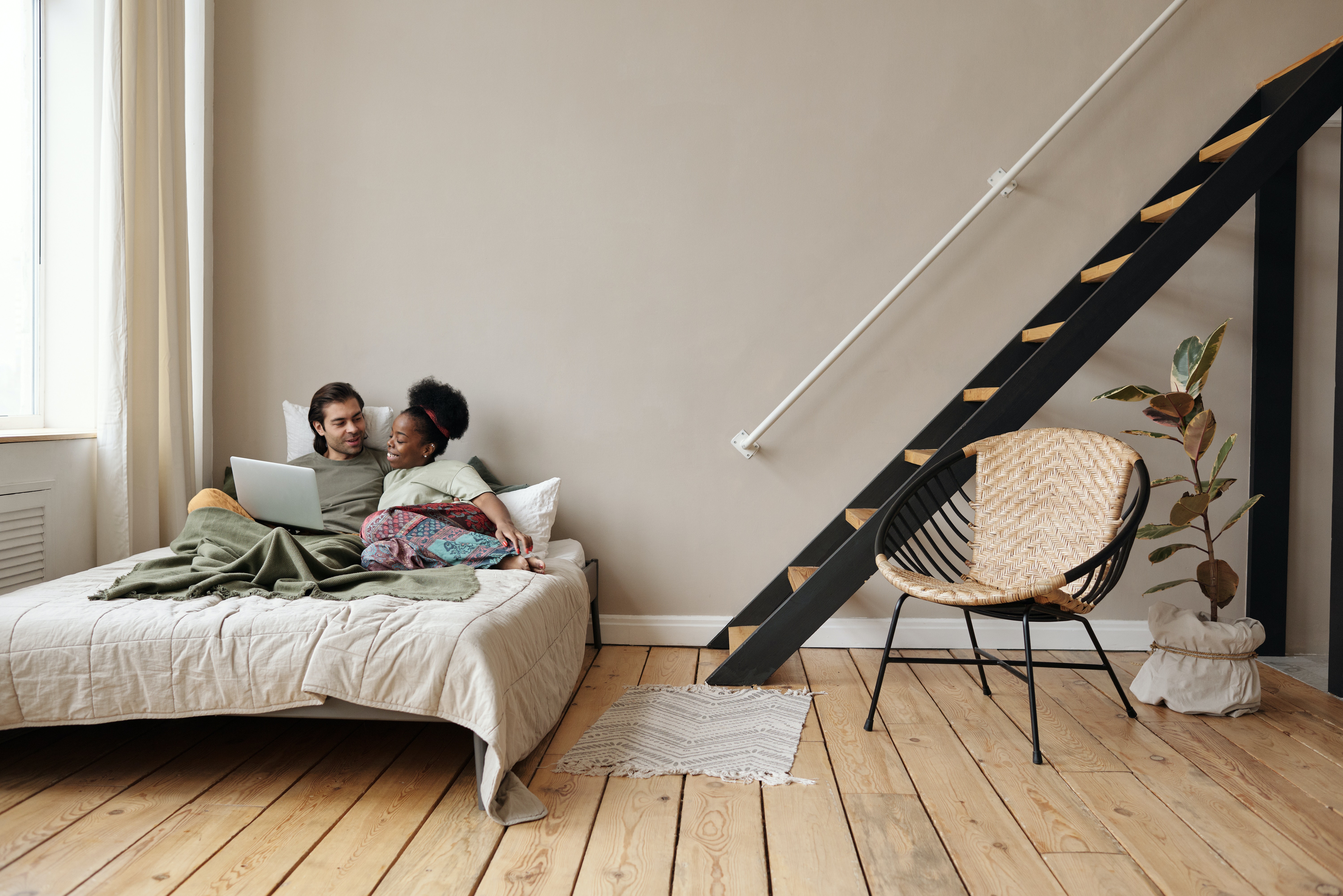 A young couple watches a movie in bed.